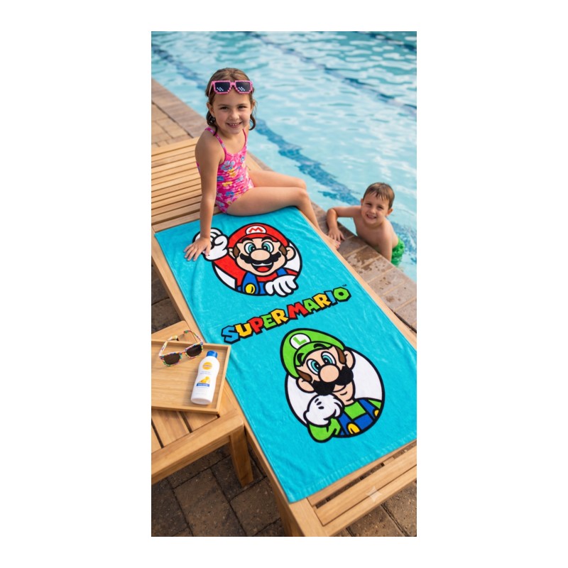 Toalla de piscina infantil azul de Super Mario y Luigi sobre una tumbona con niños jugando al agua