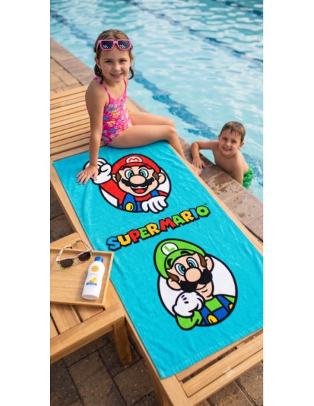 Toalla de piscina infantil azul de Super Mario y Luigi sobre una tumbona con niños jugando al agua