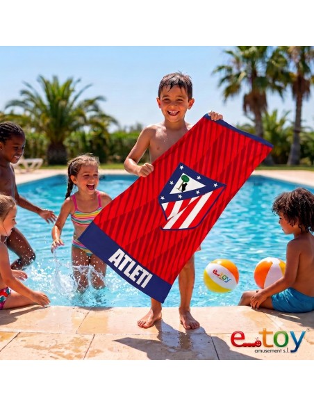 Niño mostrando sonriente la toalla de microfibra del Atlético de Madrid en una piscina
