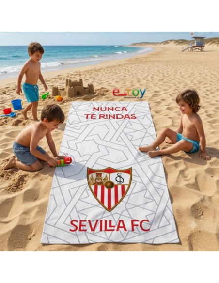 Toalla de playa oficial Sevilla FC con escudo y lema 'Nunca te Rindas', niños jugando en la arena.