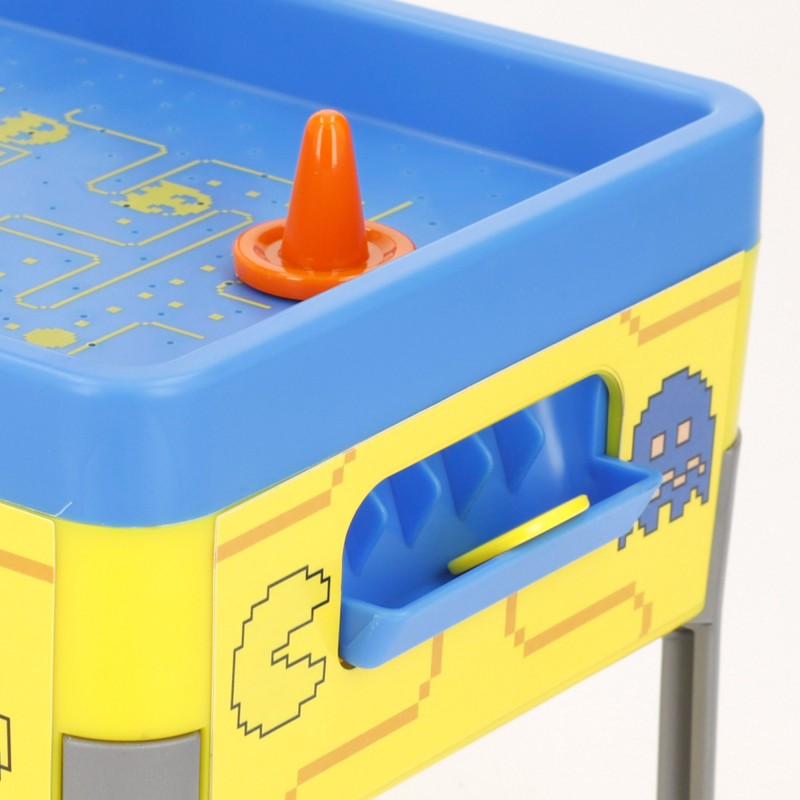 Primer plano del área de portería y pulsador naranja en la mesa de air hockey de Pac-Man.
