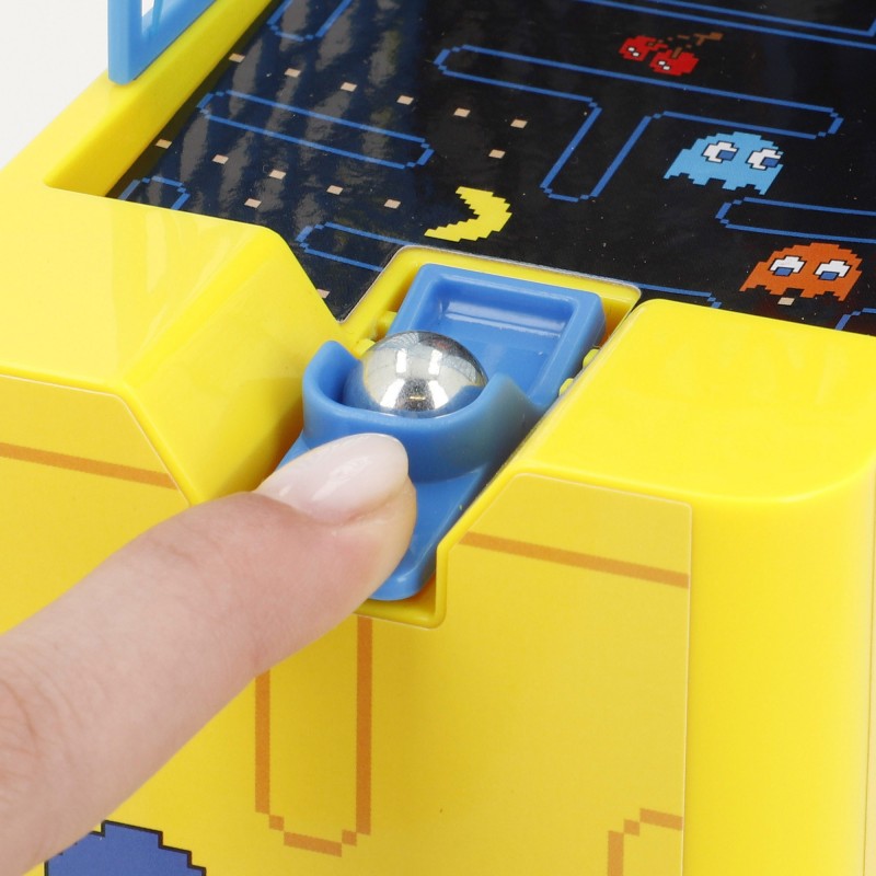 Detalle de primer plano del lanzador manual con bola metálica y gatillo azul del juego de baloncesto de mesa Pac-Man Arcade.