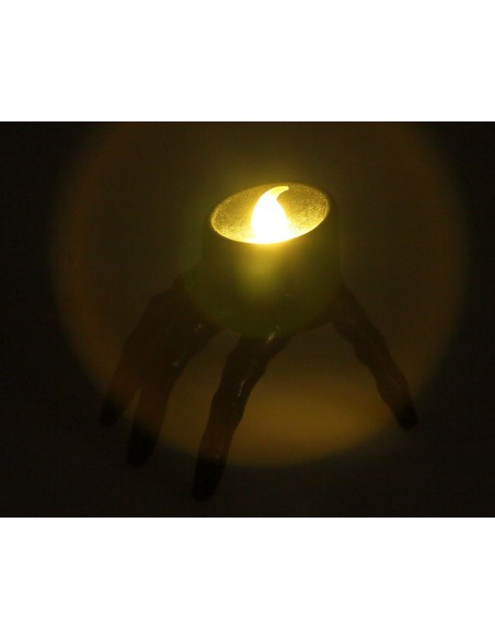 Vela LED con forma de mano de Halloween encendida en la oscuridad mostrando la luz superior cálida.